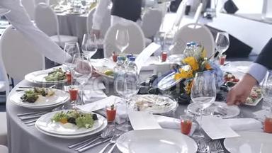 餐饮服务服务员在一次会议上把盘子和盘子放在客人的桌子上。